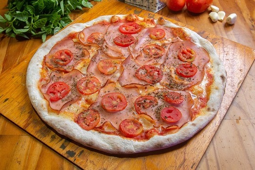 Frisch belegte Pizza mit Tomaten und Käse auf Holzbrett angerichtet